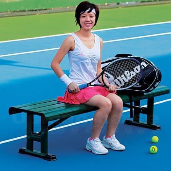 Lady seating on a bench with tennis racket